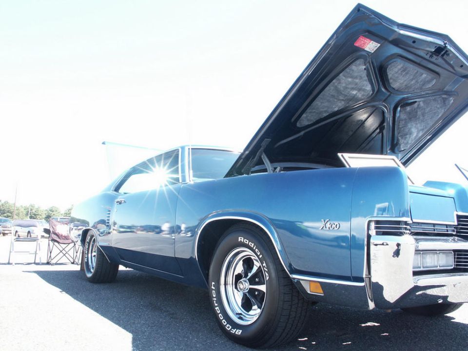 Blue classic car, hood open, showing interior. Chrome bumper and trim