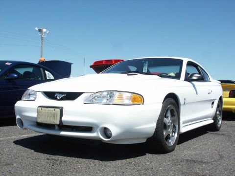 2001 Mercury Grand Marquis - A white Ford Mustang is parked at a car show, with other vehicles visible in the background.