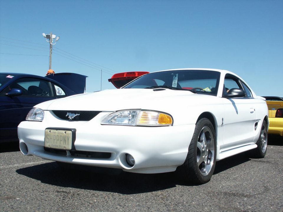 White Ford Mustang with a custom hood and license plate reading 'SHRPPNY'