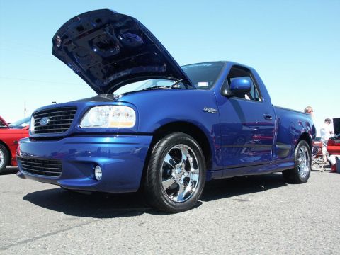 2001 Mercury Grand Marquis - A blue Ford F-150 Lightning pickup truck is displayed with its hood open at an outdoor event.