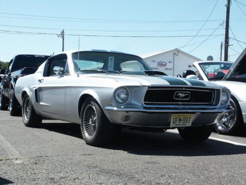 2001 Mercury Grand Marquis - A silver 1967 Ford Mustang with green racing stripes is parked at a car show.