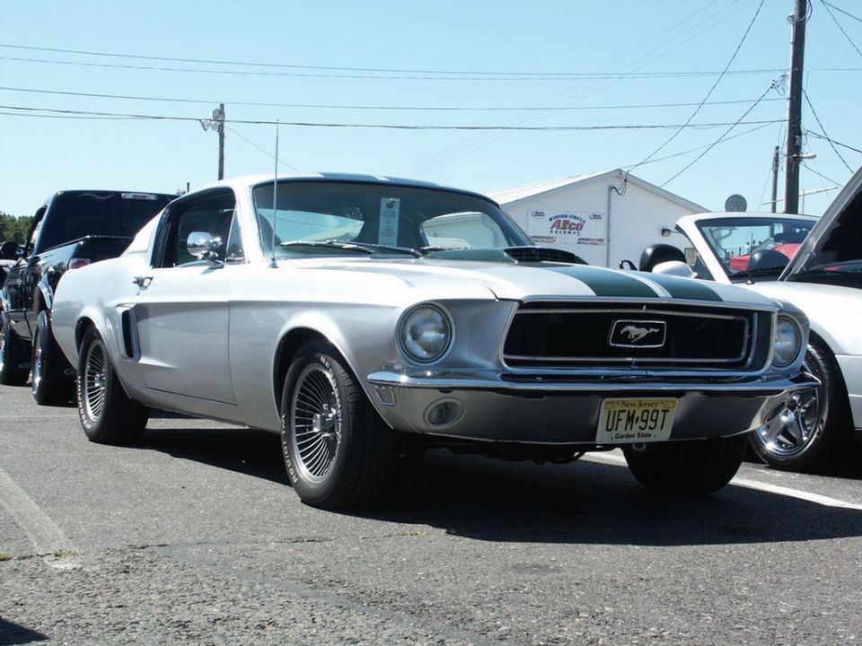 Silver 1967 Ford Mustang with green stripes, front 3/4 view, parked outdoors