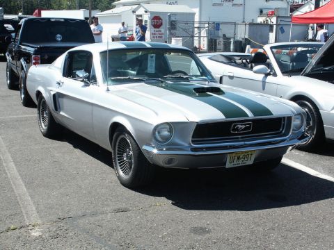 2001 Mercury Grand Marquis - A classic silver 1967 Mustang fastback with dark green racing stripes is parked at a car show.