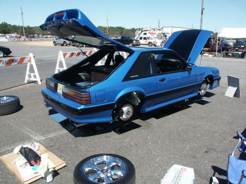 2001 Mercury Grand Marquis - Blue hatchback car with hood and trunk open, wheels removed, at a car show.