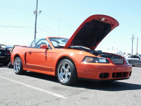 2001 Mercury Grand Marquis - An orange convertible sports car is parked with its hood open, revealing the engine bay.