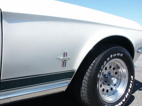 2001 Mercury Grand Marquis - Close-up of a 1967 Ford Mustang's side fender, showing the iconic running horse emblem and a Firestone tire on a custom wheel.