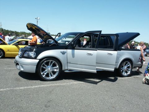 2001 Mercury Grand Marquis - A modified pickup truck is displayed with its hood and doors open at an outdoor car show.