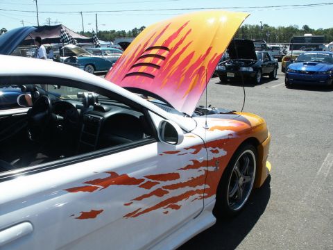 2001 Mercury Grand Marquis - A customized Ford Mustang with flame graphics is displayed at an outdoor car show with other vehicles present.