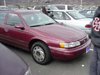 1993 Ford Taurus - A maroon 1993 Ford Taurus station wagon is parked in a lot with other vehicles.