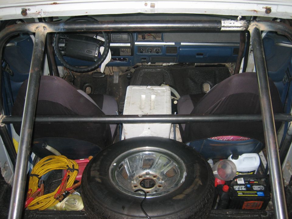 1994 Ford Bronco interior with roll cage, spare tire, cooler, and jumper cables
