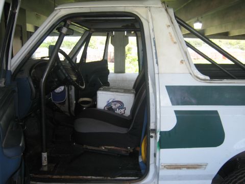 1994 Ford Bronco - The interior of a white Ford Bronco is shown, a roll cage and bucket seats.