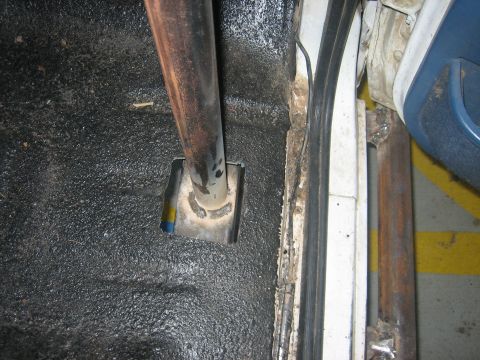 1994 Ford Bronco - Close-up of a roll cage mount on the interior floor of a vehicle, with visible welding and textured coating.