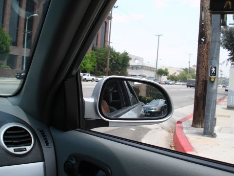1993 Ford Taurus - Side mirror reflection of a dark sedan on a city street.