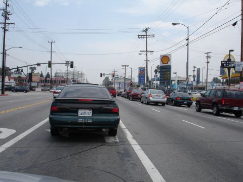 1993 Ford Taurus - A green sedan with a spoiler is seen from behind in a line of traffic on a cloudy day.