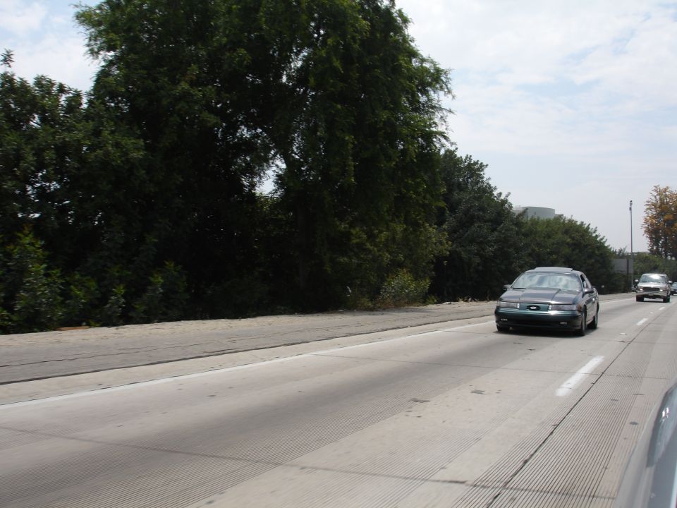 Dark sedan driving on a highway, seen from a low angle
