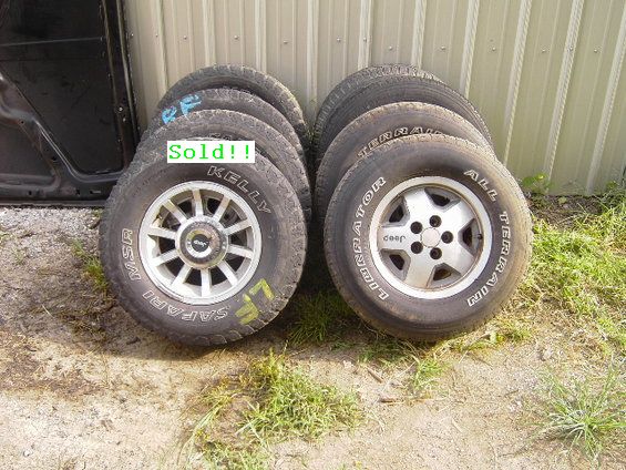 Four Jeep wheels with tires stacked, one set is MSR Safari, the other is Jeep All Terrain