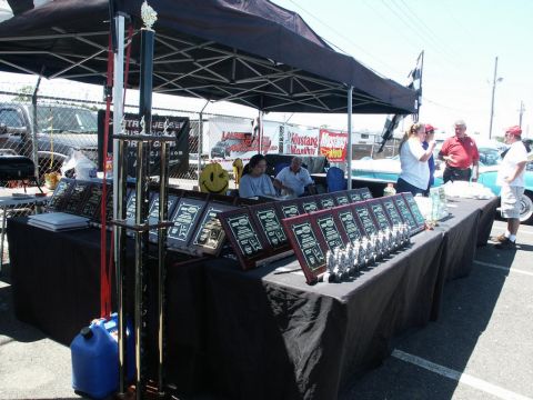 2001 Mercury Grand Marquis - A display table at a car show features numerous trophies and awards, with attendees gathered around.