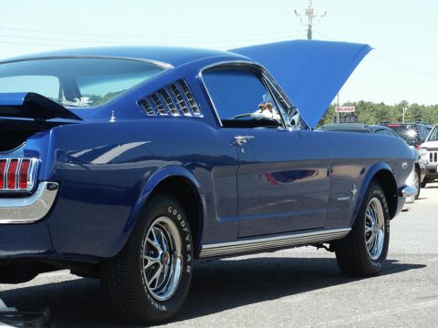 2001 Mercury Grand Marquis - A blue 1965 Ford Mustang fastback is displayed with its hood open at a car show.