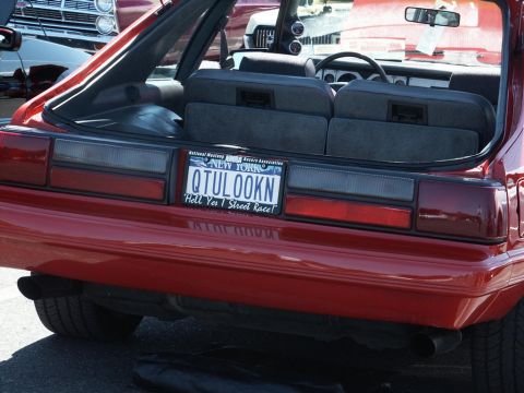 2001 Mercury Grand Marquis - Rear view of a red hatchback car with a custom New York license plate and a partial view of another vehicle.