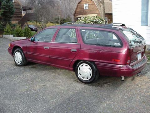 1993 Ford Taurus - A maroon station wagon is parked outside a house, with another car visible in the background.
