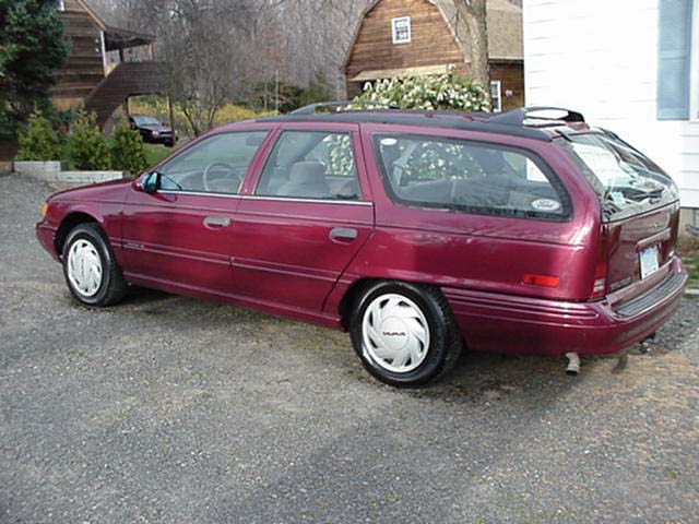 Maroon station wagon parked on gravel, seen from the rear quarter