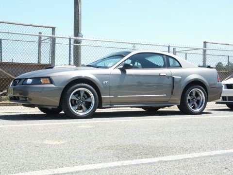 2001 Mercury Grand Marquis - A gray 2001 Ford Mustang GT is shown from the side, with a portion of another vehicle visible in the background.