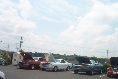 1985 Ford Crown Victoria LTD - A collection of vintage automobiles are displayed with their engines accessible under a partly cloudy sky.