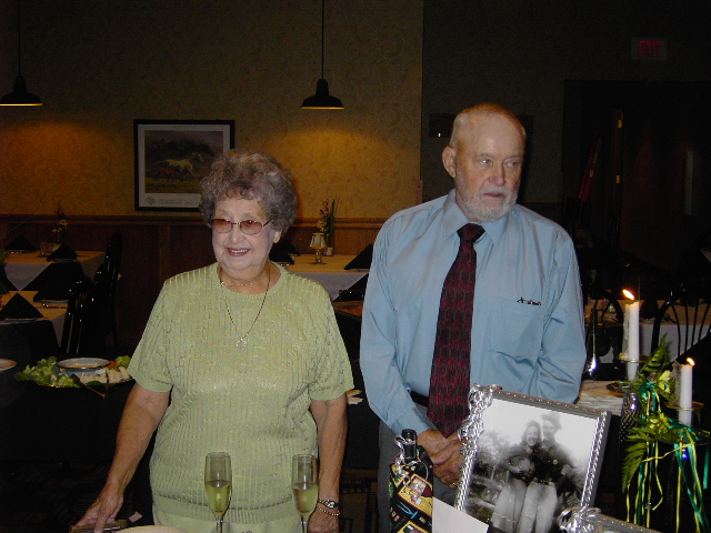 Couple standing by a table with champagne glasses and a framed photo