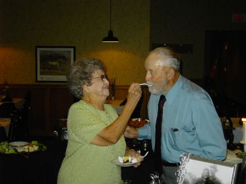 1991 Ford Bronco - An elderly woman feeds a piece of cake to an elderly man at a celebratory event.