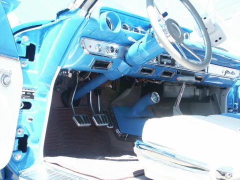 2001 Mercury Grand Marquis - The interior of a classic car features a bright blue dashboard and steering wheel, with fuzzy dice hanging from the column.