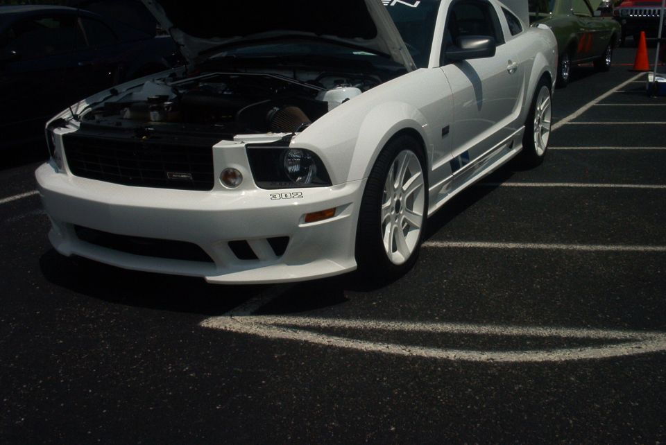 White Ford Mustang with hood open, showing engine. Visible text '302'