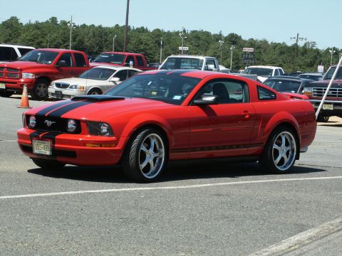 2001 Mercury Grand Marquis - This red Ford Mustang coupe, likely a 2005 model, is parked in a lot with other vehicles visible.