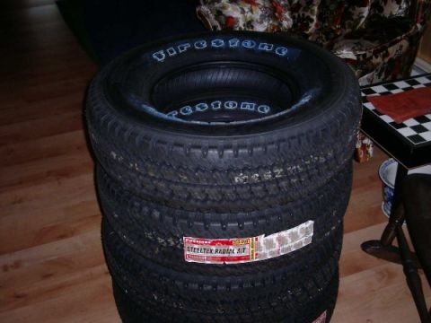 1992 Ford Bronco - A stack of four tires, with the brand name Firestone visible on the sidewall of the top tire.