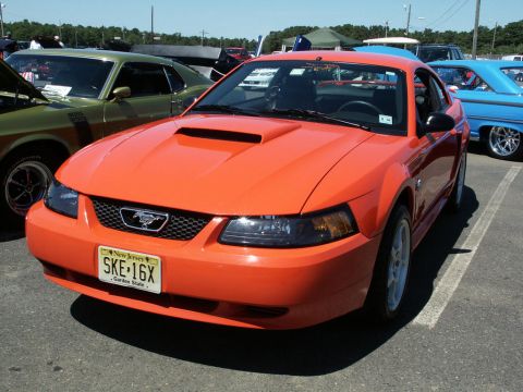 2001 Mercury Grand Marquis - Orange Ford Mustang at a car show, with a green car and blue car visible.