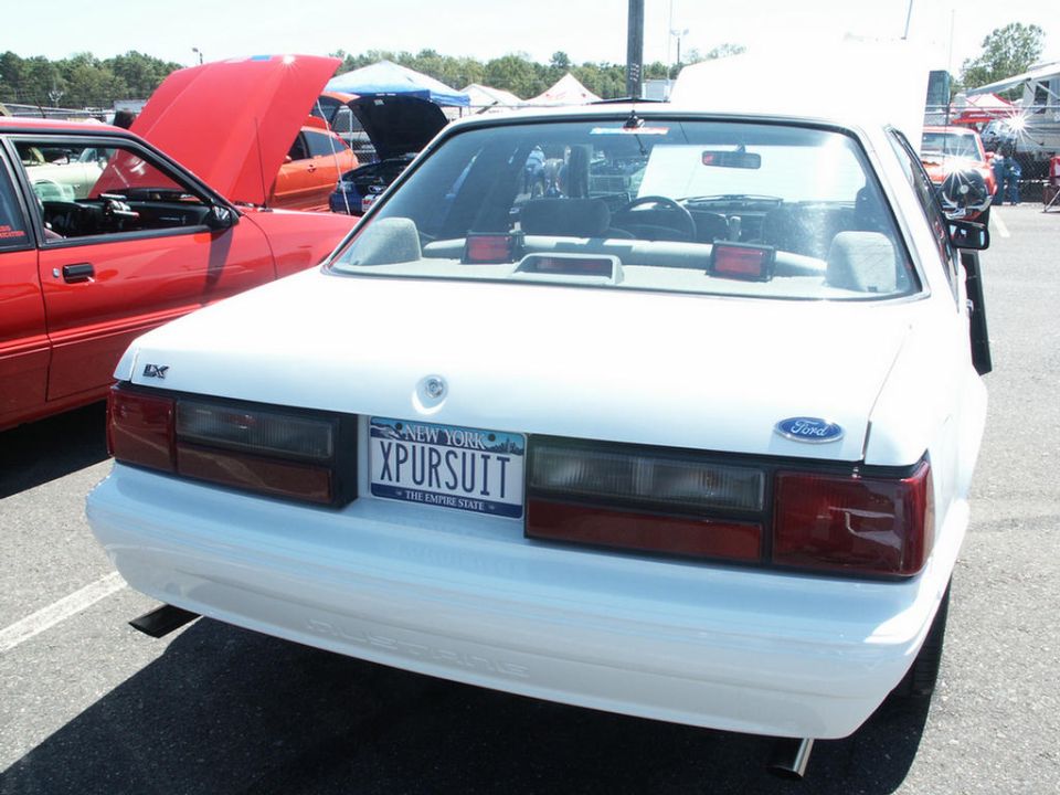 White Ford sedan rear with New York license plate 'XPURSUIT'