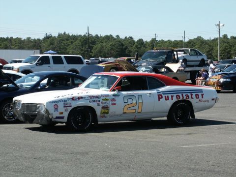 2001 Mercury Grand Marquis - A white Mercury race car with sponsor decals and the number 21 is parked in a lot with other vehicles.