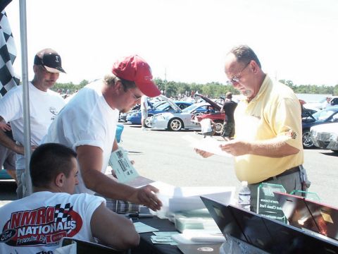 2001 Mercury Grand Marquis - People interact at a table with cars visible in the background at an outdoor event.
