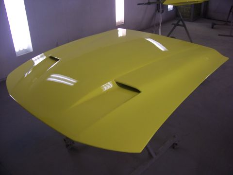 2002 Ford Mustang - A yellow 2002 Ford Mustang hood with dual vents is displayed in a paint booth.