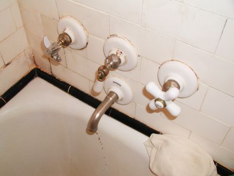 1992 Ford Taurus - A close-up view of a vintage bathtub faucet assembly, showing the hot, cold, and shower controls.