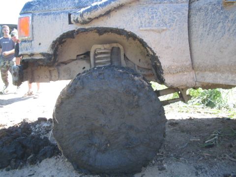 1990 Ford Bronco - This 1990 Ford Bronco is heavily covered in mud, with its large tire and fender prominently displayed.
