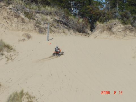 1993 Ford Bronco - An ATV navigates a sandy slope, kicking up dust as it descends.