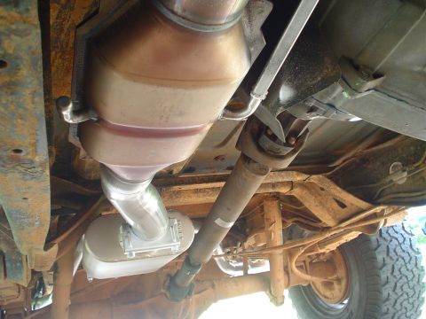 1984 Ford Bronco - Undercarriage view of a vehicle's exhaust system and drivetrain components.