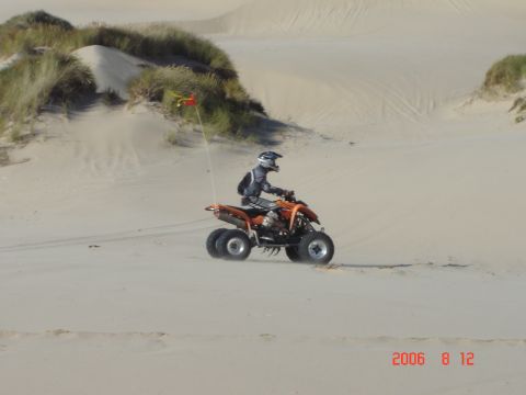 1993 Ford Bronco - ATV rider on sand dunes with a flag. Watermark indicates date and website.