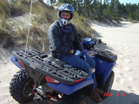1993 Ford Bronco - A person sits on a blue ATV on a sandy dune, ready for off-road adventure.