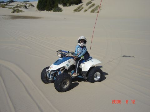 1993 Ford Bronco - A child wearing a helmet and goggles rides an ATV through sandy terrain.