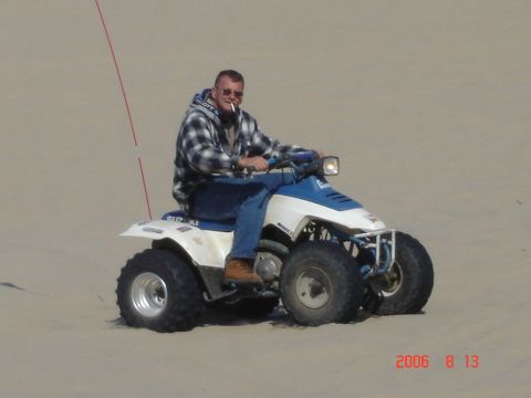 1993 Ford Bronco - A man rides a Suzuki ATV through a sandy landscape on a sunny day.