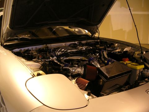 1996 Ford Probe - Close-up view of a modified car engine bay, highlighting custom chrome parts and air intake system.