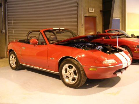 1996 Ford Probe - Red convertible with white racing stripes and hood open, with another red car visible behind it.