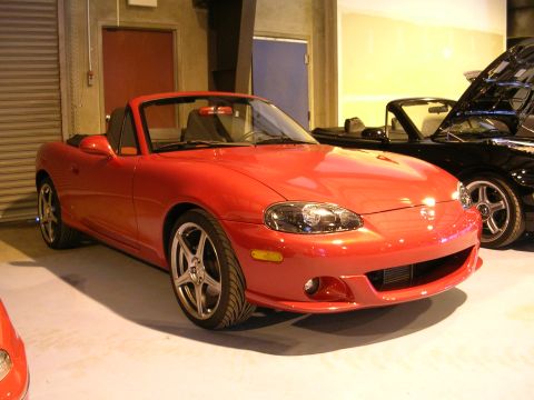 1996 Ford Probe - A red convertible sports car is parked next to a black convertible with its hood open inside a garage.