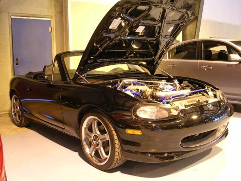 1996 Ford Probe - A black convertible with its hood open, revealing the engine bay. Another vehicle is visible in the background.